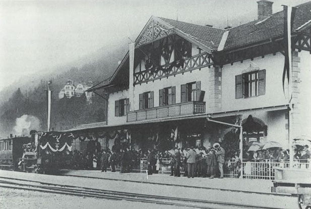 Mit Girlanden gekränzt fährt am 1. Mai 1902 der erste Zug in den neuen Tegernseer Bahnhof ein.